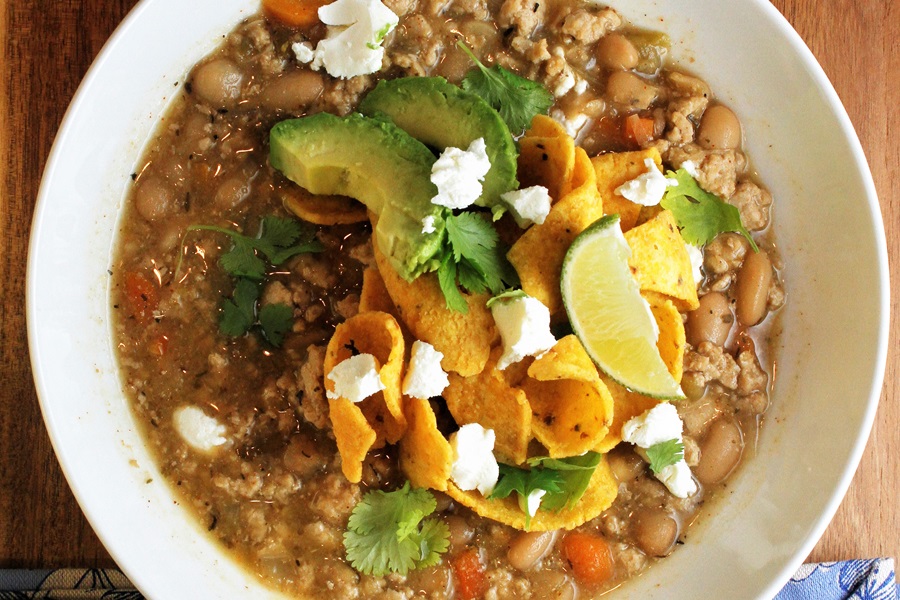 Crockpot Ground Chicken Chili Recipe Overhead View of a Bowl of Chili Topped with Avocado Slices, Frito Chips, and a Lime Wedge