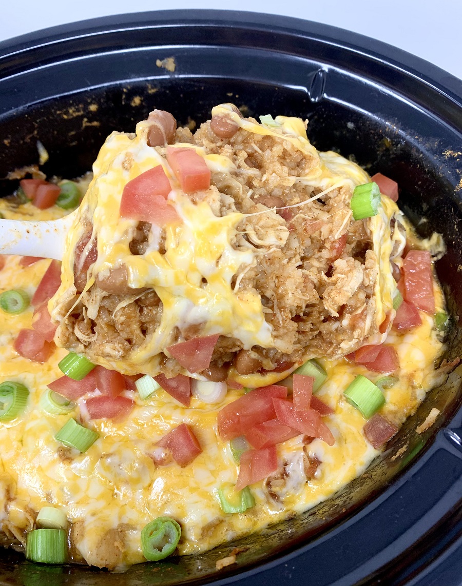 Crockpot Chicken and Rice Burrito Bowl Recipe Person Lifting a Serving Out of the Crockpot
