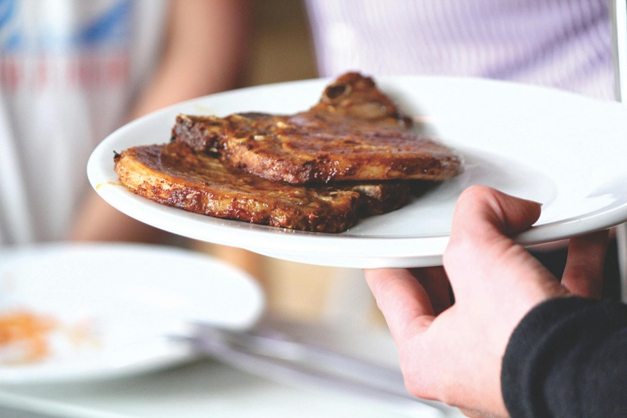 Easy Instant Pot Pork Chops Recipes a Person Holding a White Plate with Two Pork Chops on it